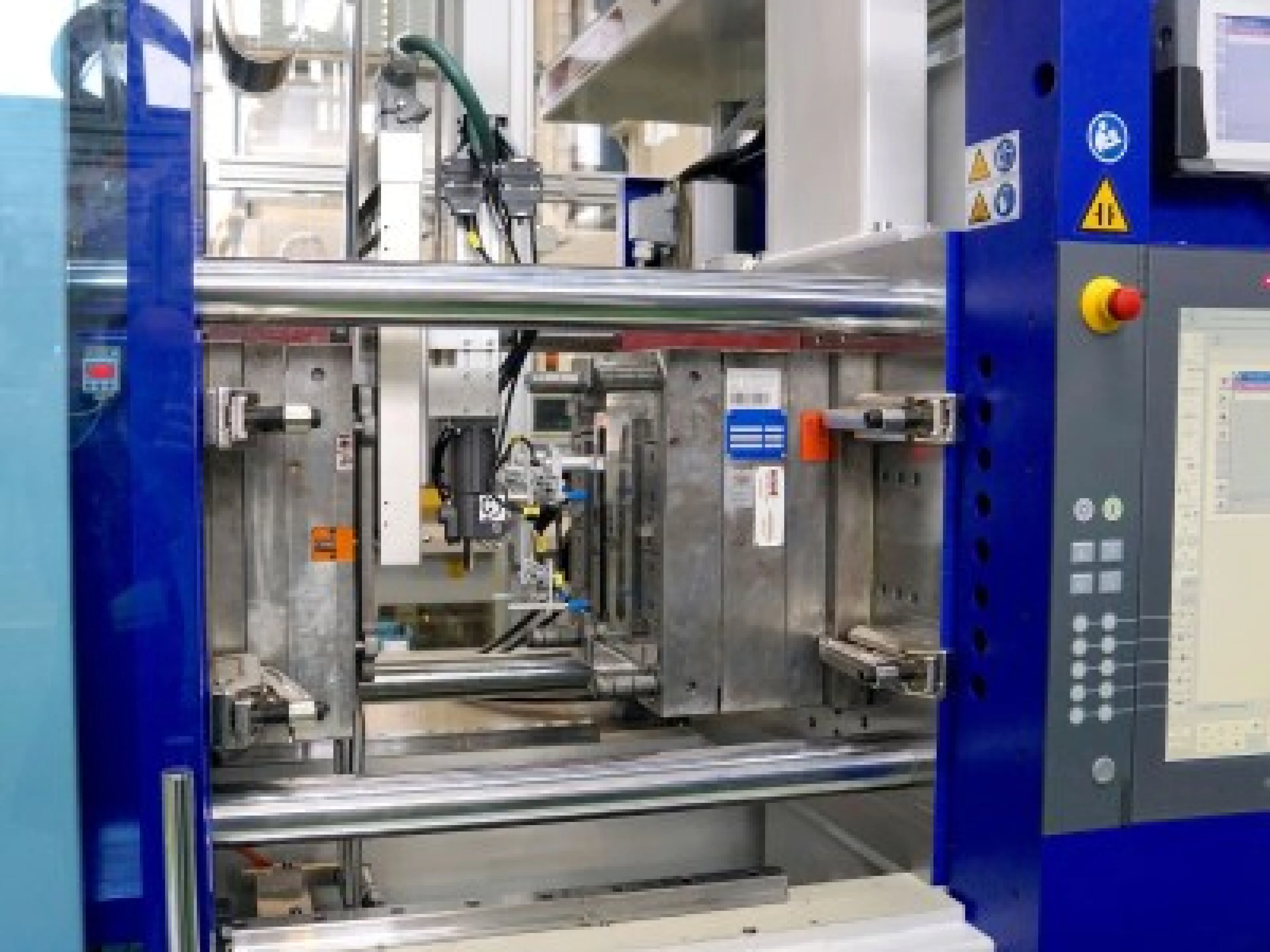 Beide Spritzgießmaschinen sind mit Rolle-zu-Rolle-Folienvorschubeinheiten ausgerüstet. Die Roboter tragen eine Folien-Wärmeplatte und gegenüber davon den Sauggreifer zur Fertigteil-Entnahme