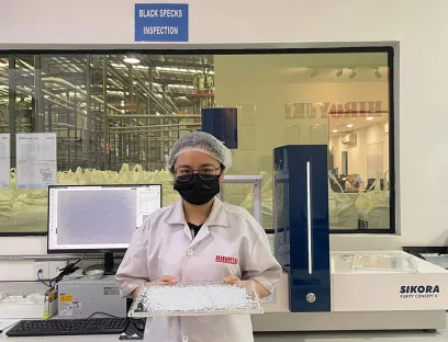 Angel Loh, Chemikerin bei Hiroyuki, mit rPET-Pelletproben, die mit dem Inspektionssystem von Sikora geprüft werden 
